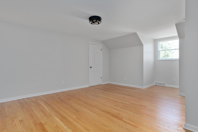 bonus room with visible vents, baseboards, lofted ceiling, and light wood-style flooring