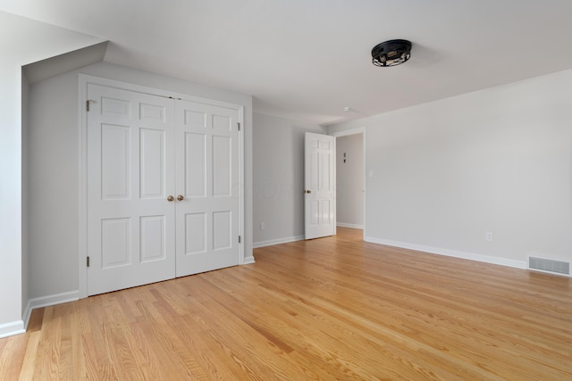 unfurnished bedroom featuring light wood finished floors, visible vents, a closet, and baseboards