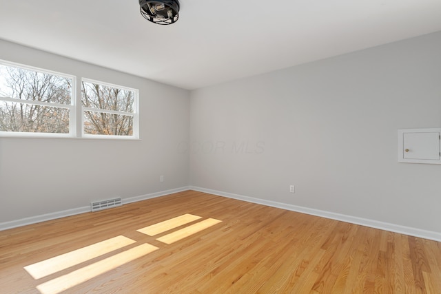 spare room featuring visible vents, baseboards, and light wood-style floors