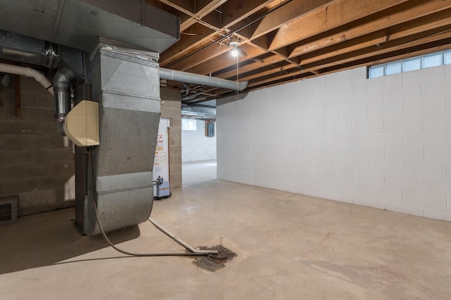 basement featuring water heater, a healthy amount of sunlight, and concrete block wall