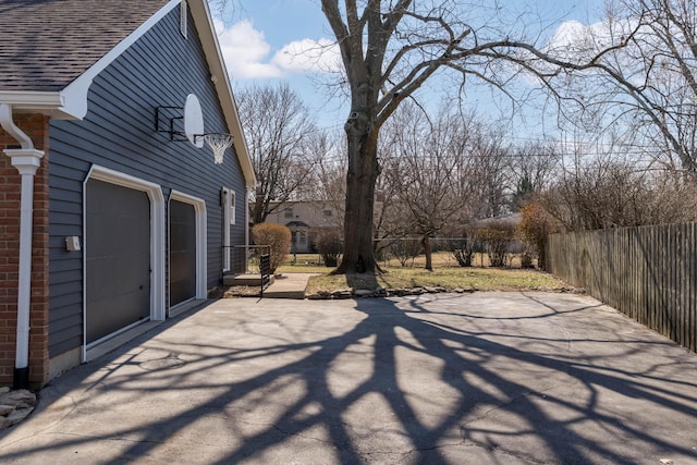 view of patio / terrace with concrete driveway, fence, and a garage