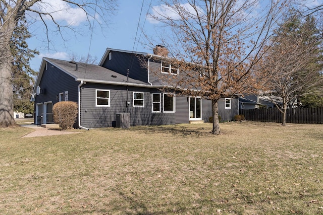 rear view of house featuring a lawn, a chimney, and fence