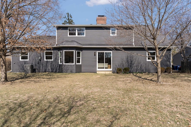 back of house featuring a lawn and a chimney