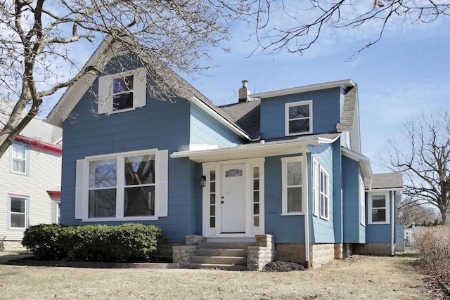 view of front of house featuring entry steps, a chimney, and roof with shingles