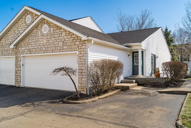 view of front of property featuring aphalt driveway, stone siding, an attached garage, and roof with shingles