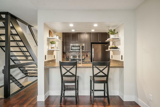 kitchen with dark wood-type flooring, open shelves, tasteful backsplash, stainless steel appliances, and dark brown cabinets