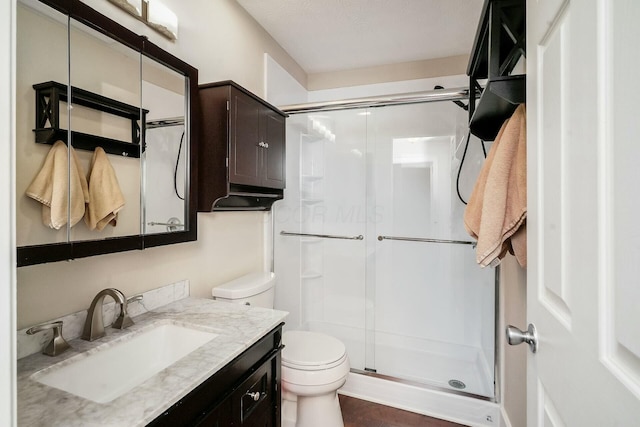 bathroom featuring a shower stall, toilet, and vanity