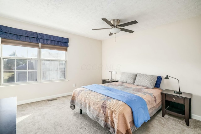 carpeted bedroom featuring a ceiling fan, baseboards, visible vents, and a textured ceiling