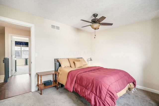 bedroom featuring visible vents, carpet, ceiling fan, and a textured ceiling