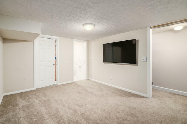 finished below grade area featuring baseboards, carpet floors, and a textured ceiling