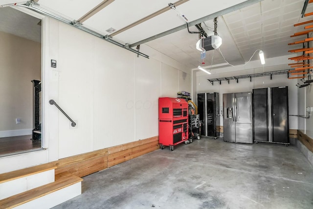 garage with a garage door opener and stainless steel fridge