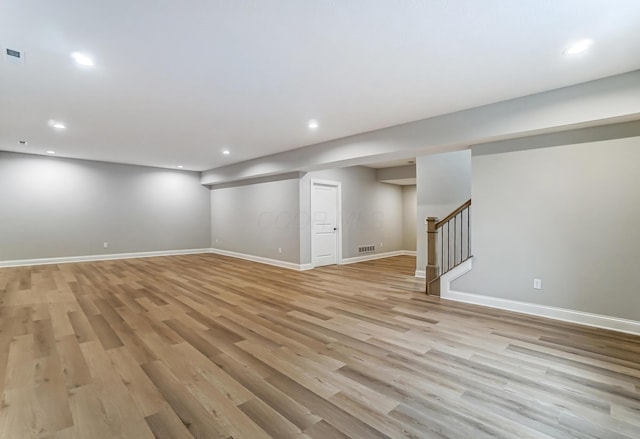 finished basement featuring recessed lighting, light wood-type flooring, visible vents, and stairs