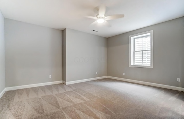 empty room with baseboards, carpet, visible vents, and ceiling fan