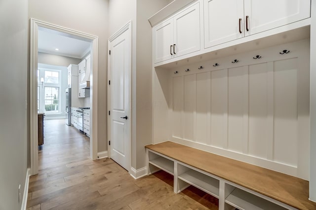 mudroom with baseboards, light wood-type flooring, and ornamental molding