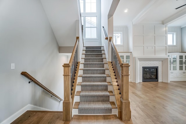 staircase featuring a fireplace, baseboards, and wood finished floors