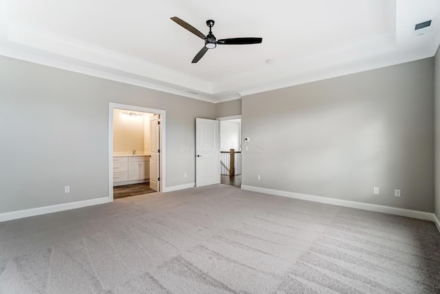 unfurnished bedroom with a ceiling fan, baseboards, carpet floors, a raised ceiling, and connected bathroom