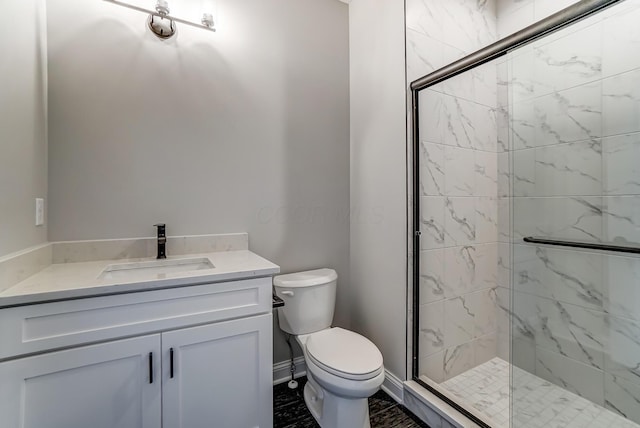 full bathroom with vanity, toilet, baseboards, and a marble finish shower