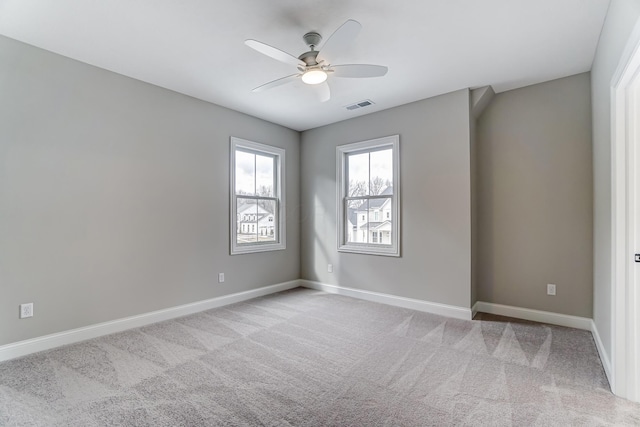 unfurnished room with visible vents, light carpet, baseboards, and ceiling fan