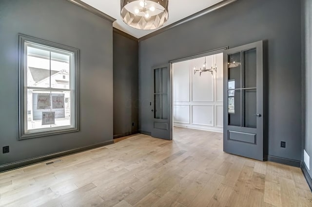 foyer featuring baseboards, visible vents, an inviting chandelier, light wood-style flooring, and ornamental molding