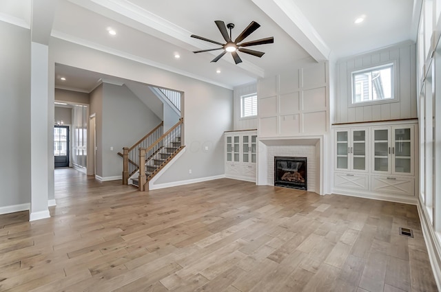 unfurnished living room featuring a ceiling fan, stairway, baseboards, and light wood-type flooring