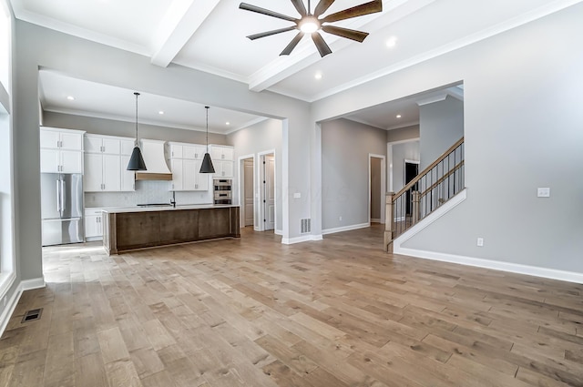 kitchen featuring a ceiling fan, light wood-type flooring, beam ceiling, stainless steel appliances, and open floor plan