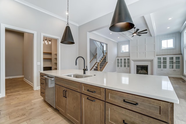 kitchen featuring a sink, ceiling fan, ornamental molding, and light wood finished floors