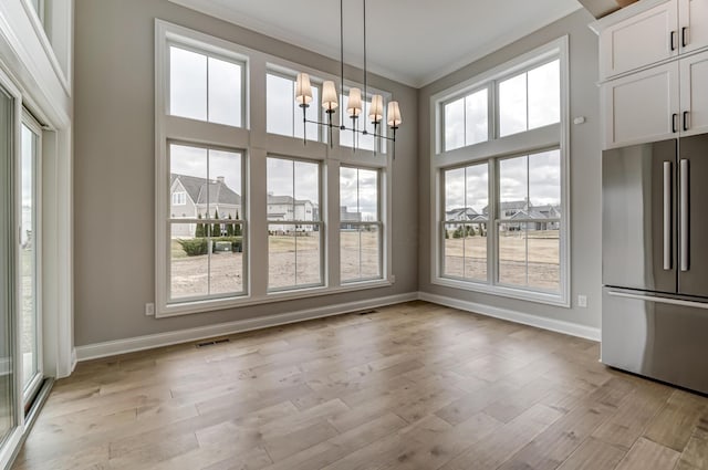 unfurnished dining area featuring visible vents, a healthy amount of sunlight, light wood-style flooring, and an inviting chandelier