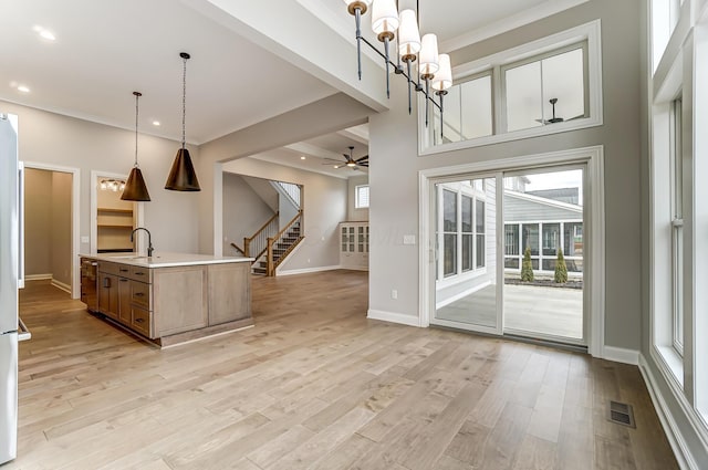 kitchen featuring light wood finished floors, visible vents, baseboards, light countertops, and a sink