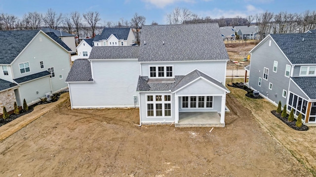 rear view of property featuring a patio area, a residential view, and a shingled roof