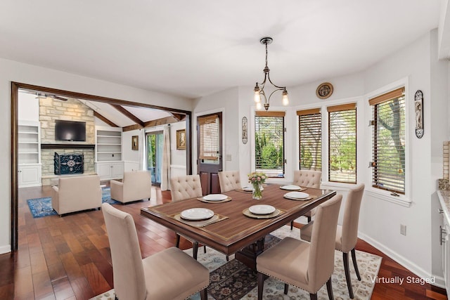 dining area with vaulted ceiling with beams, dark wood finished floors, a fireplace, and an inviting chandelier