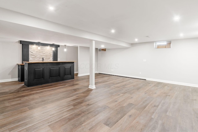 finished basement featuring wet bar, recessed lighting, light wood-style floors, and baseboards