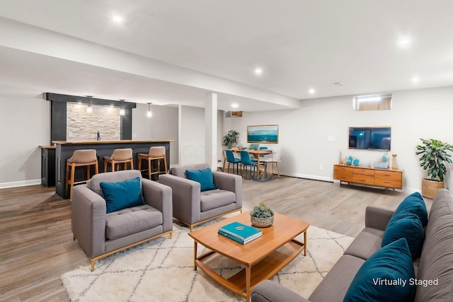 living room with light wood finished floors, recessed lighting, baseboards, and bar