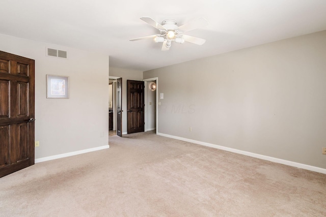 empty room with baseboards, visible vents, and light carpet