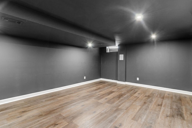 finished basement with visible vents, baseboards, and light wood-style floors