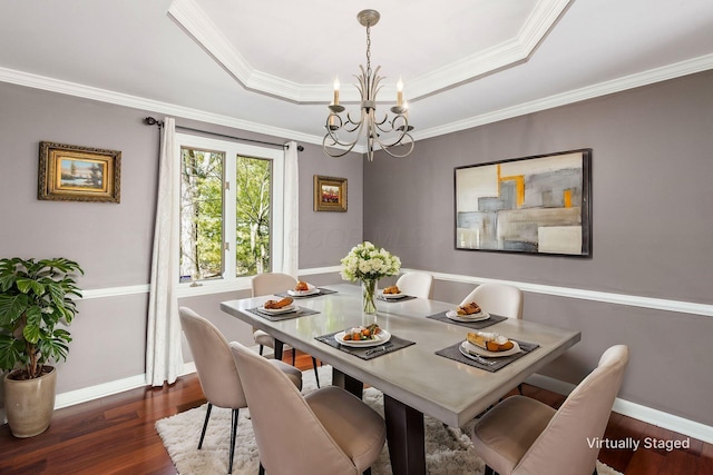 dining room with a raised ceiling, a notable chandelier, crown molding, baseboards, and dark wood-style flooring