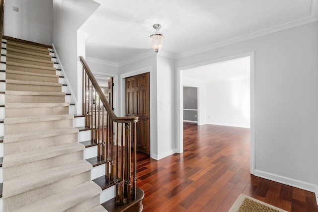 stairway featuring baseboards, an inviting chandelier, wood finished floors, and ornamental molding