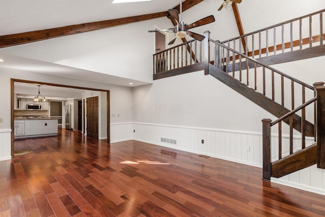 unfurnished living room featuring visible vents, ceiling fan, stairway, wainscoting, and dark wood-style floors