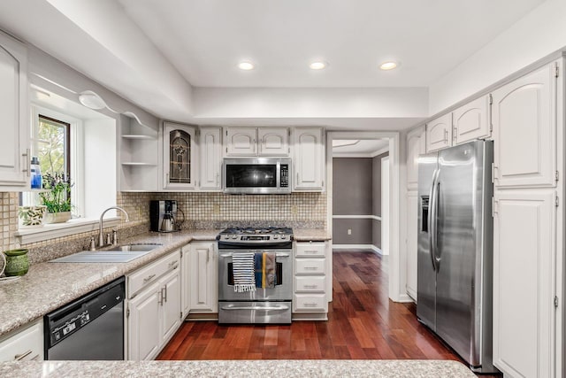 kitchen with a sink, dark wood-type flooring, light countertops, appliances with stainless steel finishes, and tasteful backsplash