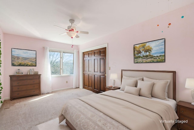 bedroom featuring a closet, baseboards, light colored carpet, and ceiling fan