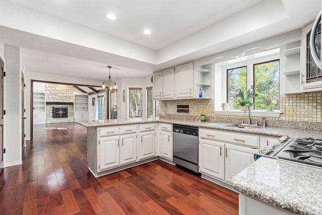 kitchen featuring a peninsula, stainless steel dishwasher, dark wood-style floors, a raised ceiling, and open shelves