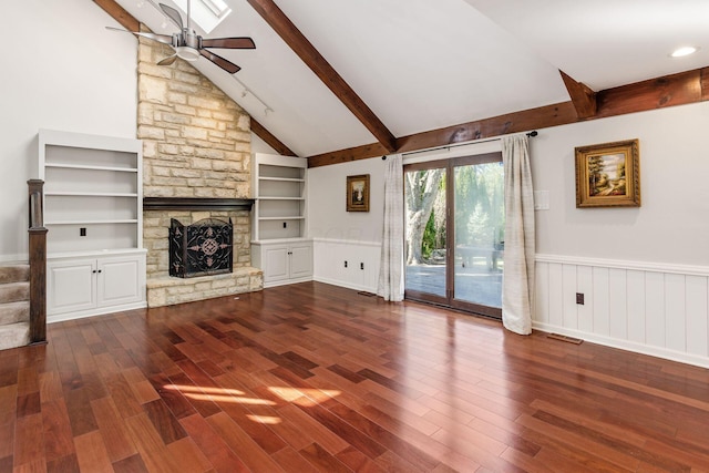 unfurnished living room with beamed ceiling, a fireplace, a ceiling fan, and wood finished floors