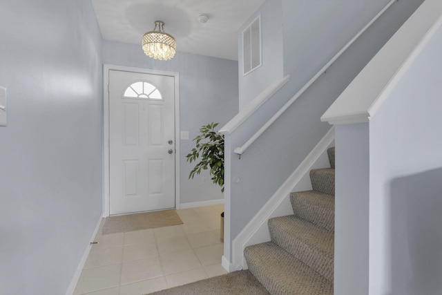 tiled entryway featuring visible vents, baseboards, a chandelier, and stairs