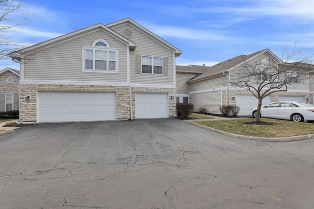 traditional-style home with aphalt driveway, stone siding, and an attached garage