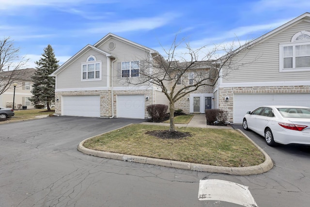 view of front of house featuring aphalt driveway, stone siding, and a garage