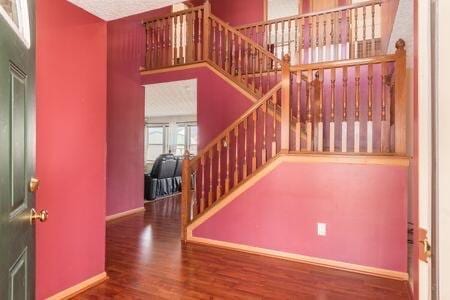 entryway with stairs, wood finished floors, and baseboards