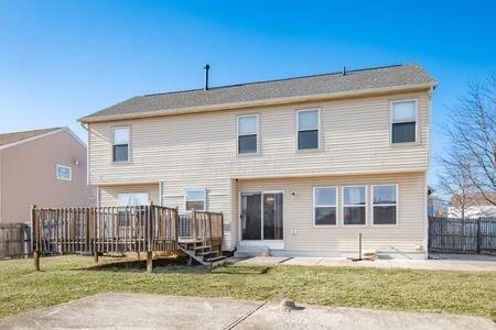 back of property with a wooden deck, a yard, and fence