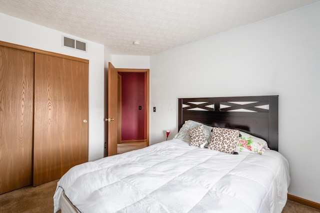 bedroom featuring visible vents, carpet floors, a textured ceiling, and a closet