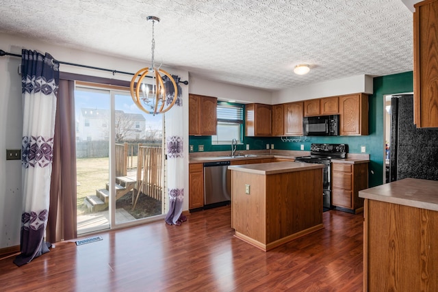 kitchen featuring visible vents, a center island, dark wood-type flooring, appliances with stainless steel finishes, and brown cabinetry