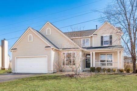 traditional-style home with a porch, a garage, a front lawn, and aphalt driveway