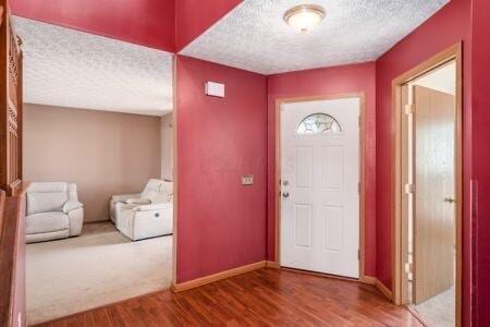 foyer entrance featuring wood finished floors, baseboards, and a textured ceiling